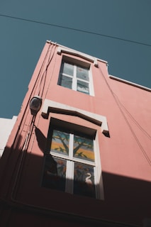 a red building with a window and a bird painted on it