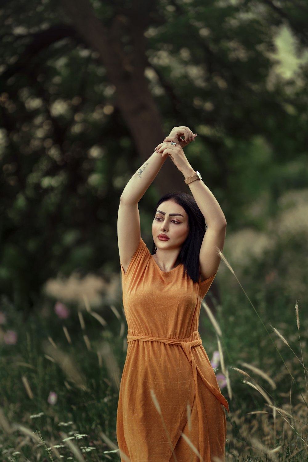 Una mujer con un vestido naranja parada en un campo