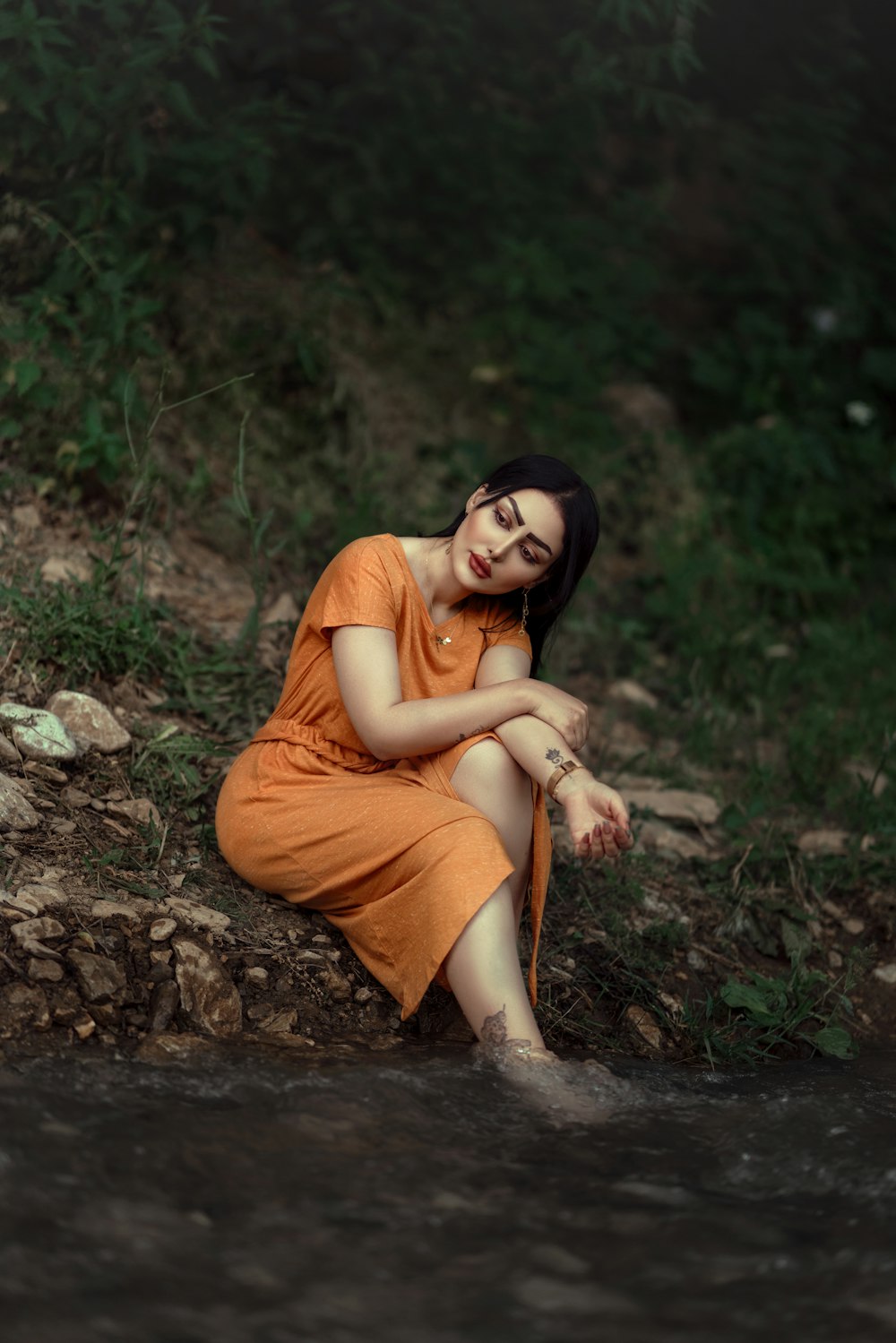 a woman in an orange dress sitting on the ground