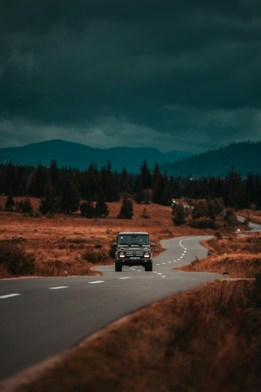 a jeep driving down a road in the middle of a field