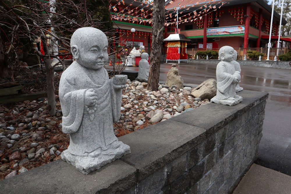 statues of buddhas sitting on a stone wall