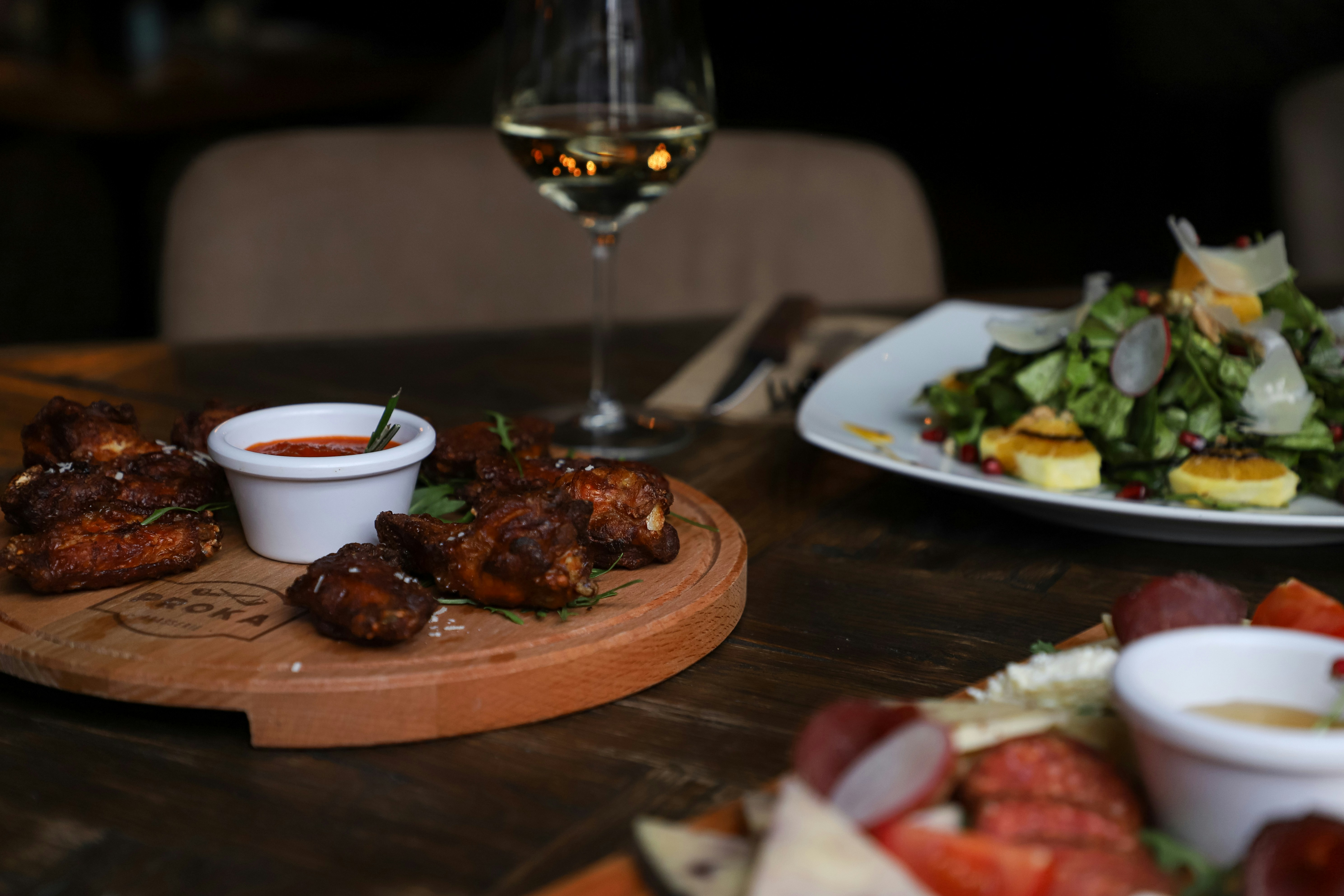 a wooden table topped with plates of food and a glass of wine