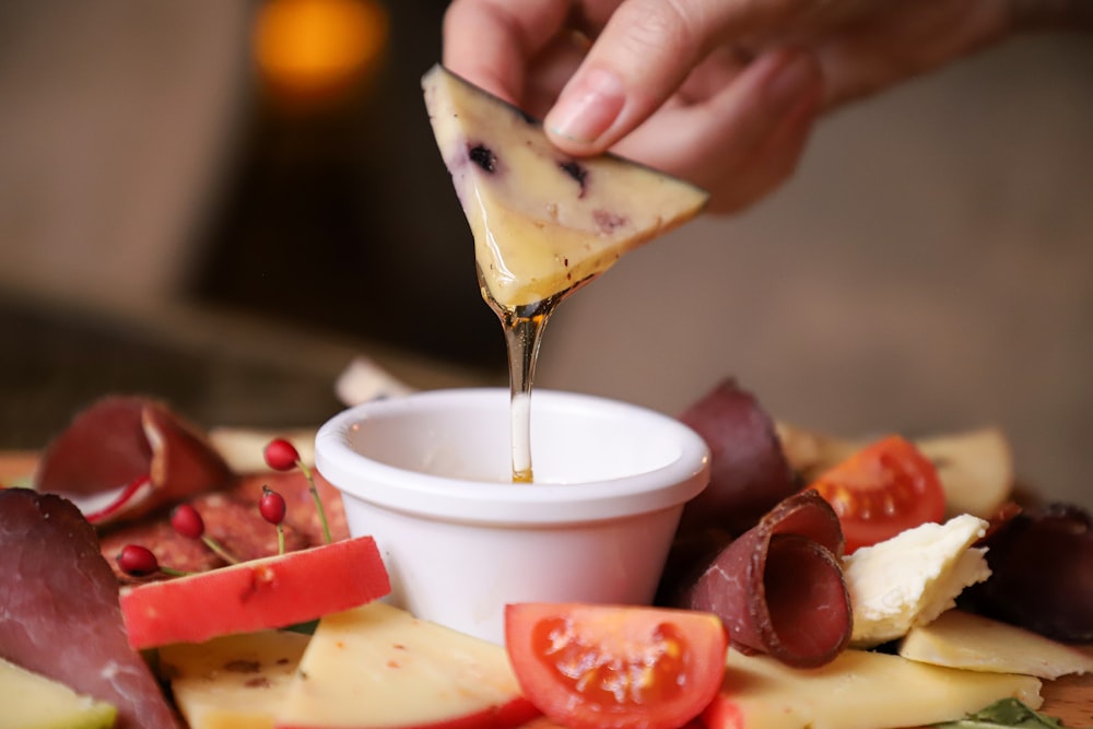 a person dipping cheese into a small bowl