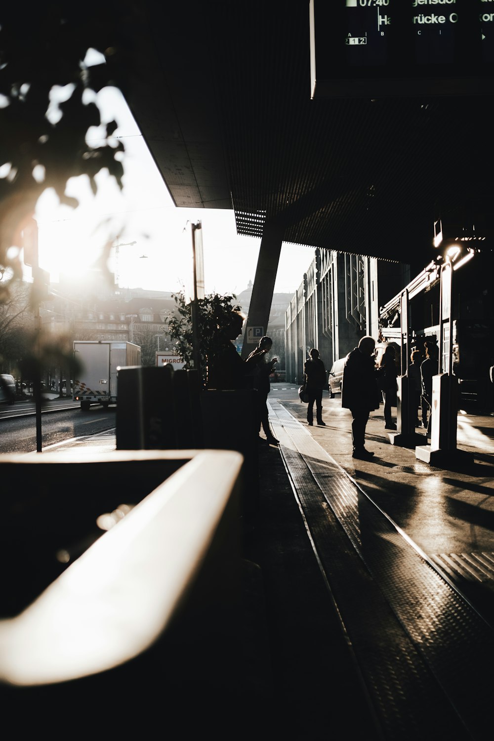 a group of people walking down a sidewalk next to a train station