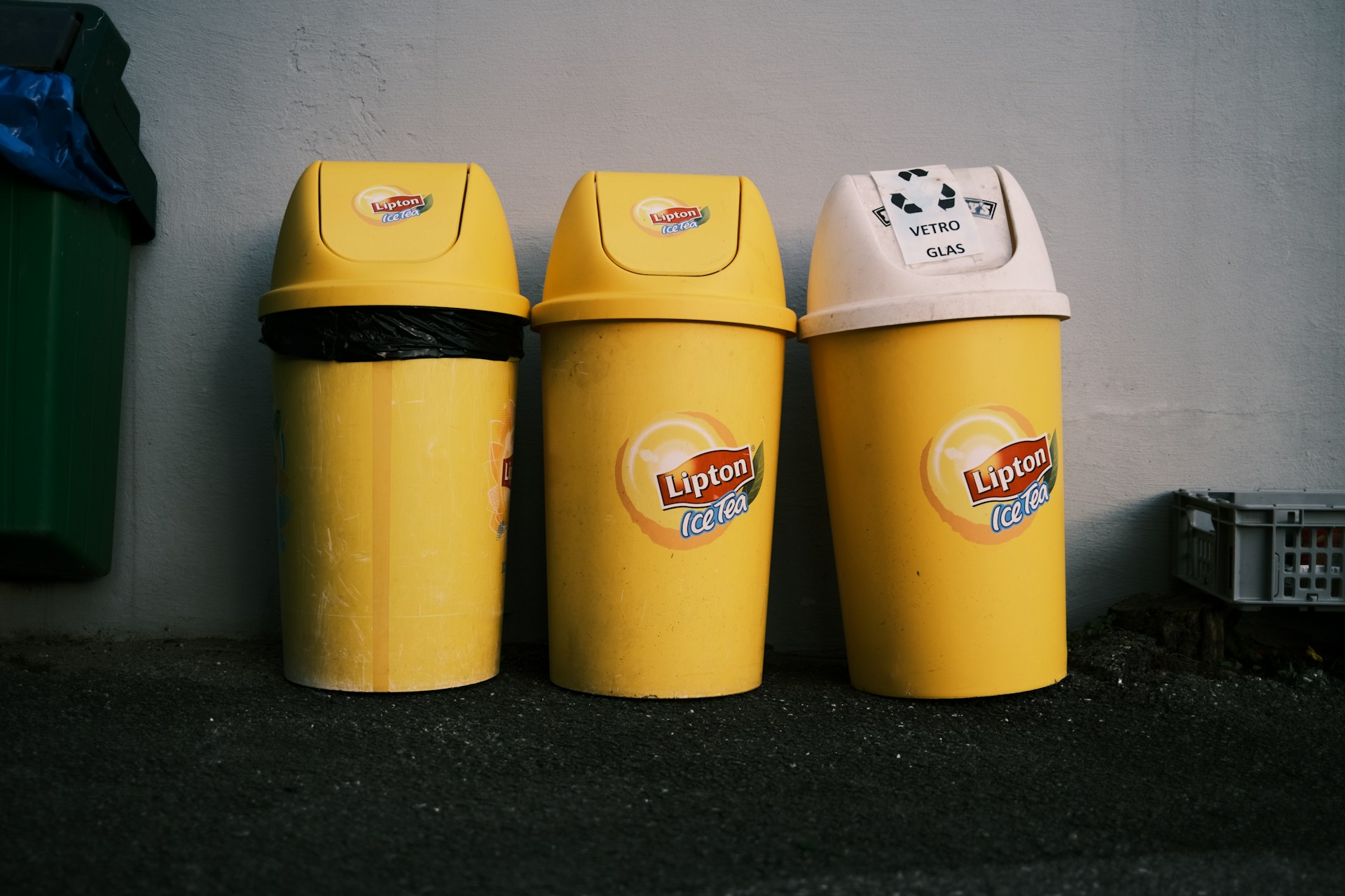 three yellow trash cans lined up against a wall