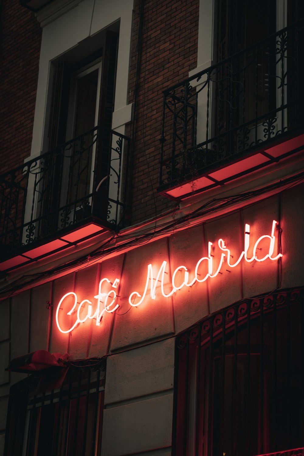 a neon sign that reads cafe madrid on the side of a building