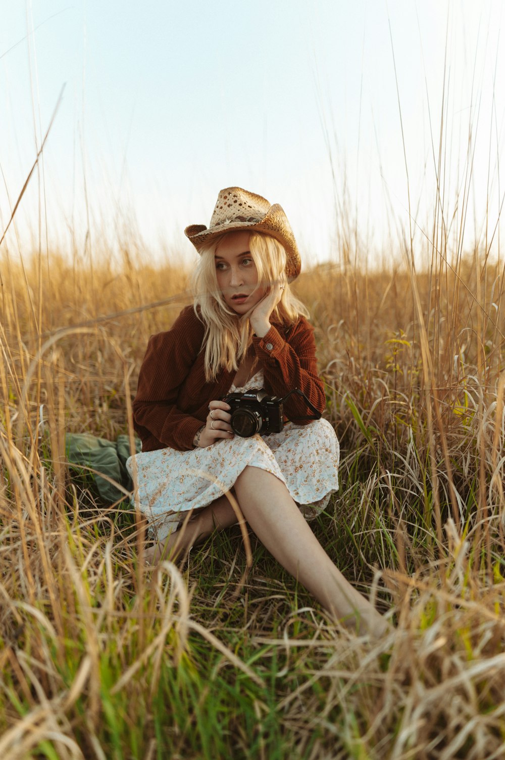 a woman sitting in a field with a camera