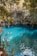 Cyclists pausing beside a crystal-clear turquoise cenote surrounded by lush jungle.