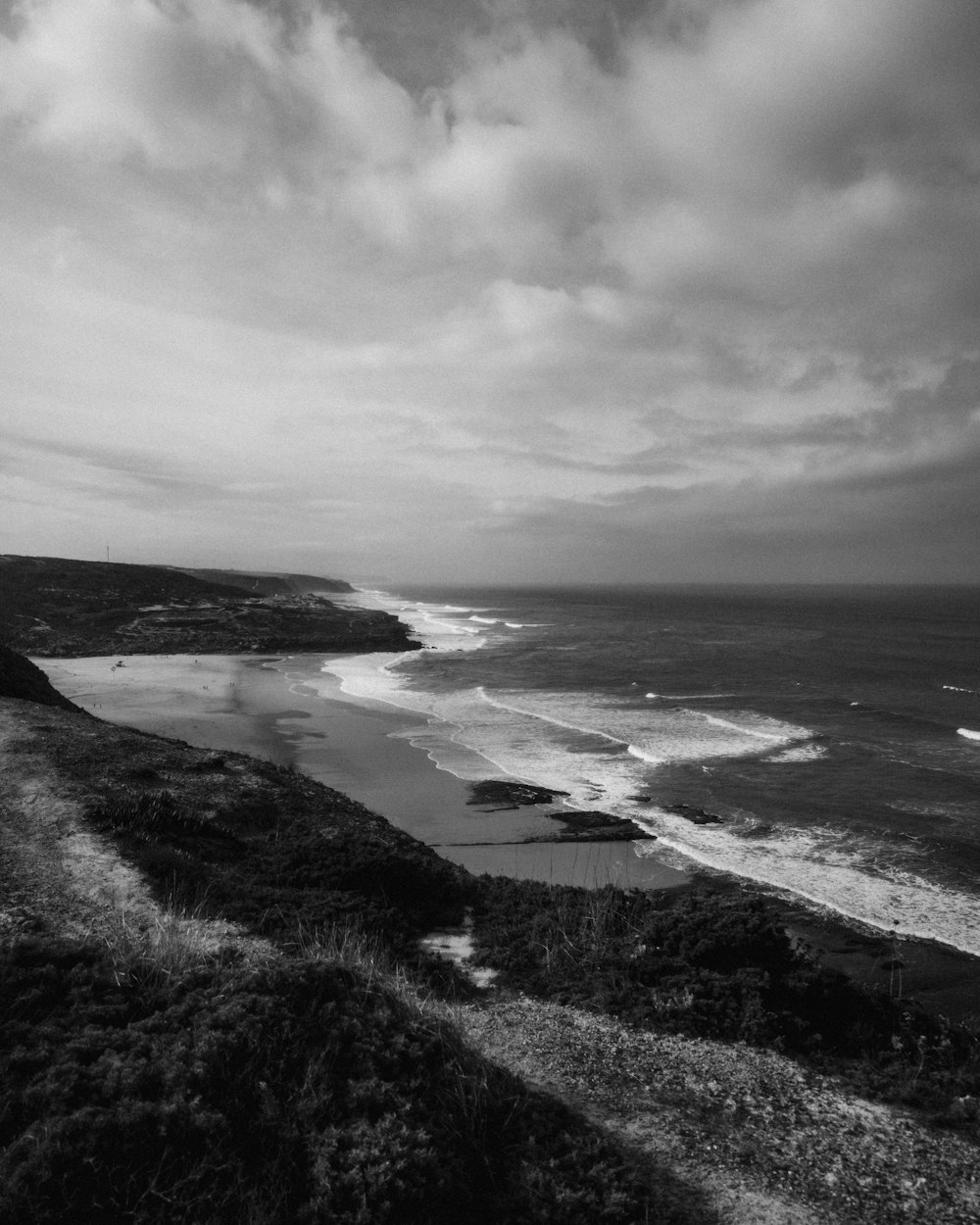 a black and white photo of a beach and ocean