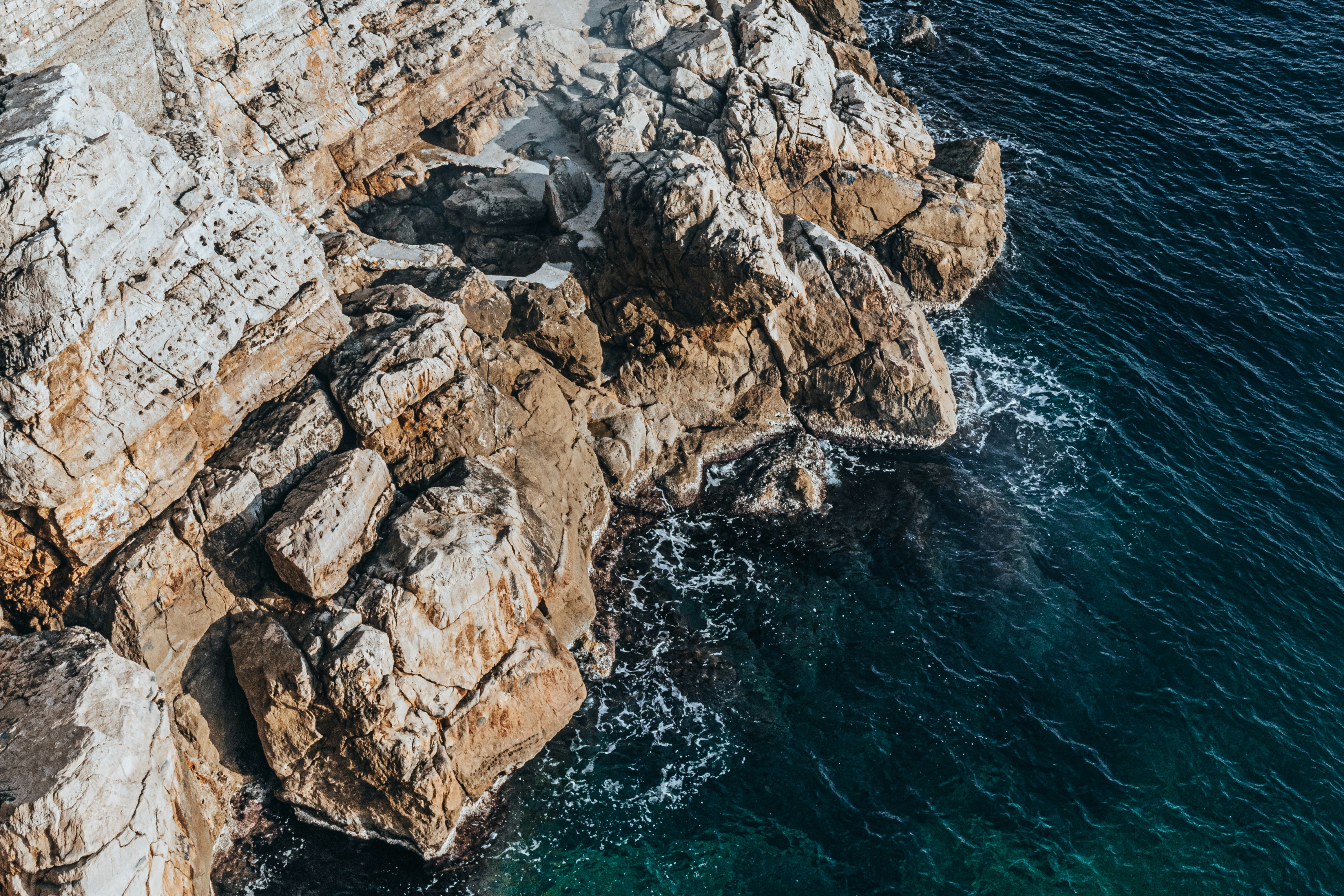 An aerial view of a rocky coastline with clear blue water