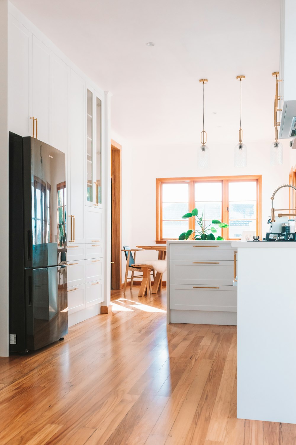 a kitchen with a black refrigerator freezer next to a wooden floor