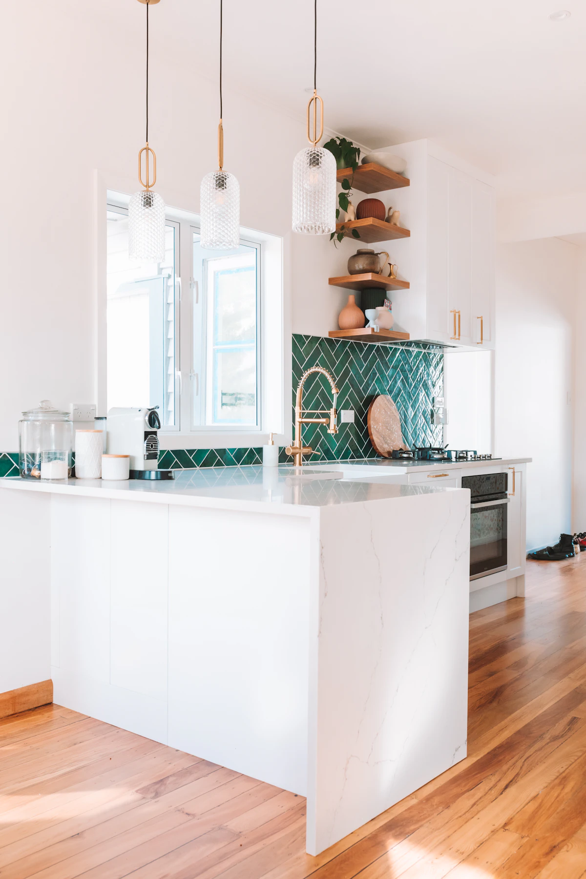 Kitchen with green herringbone backsplash above hardwood flooring.