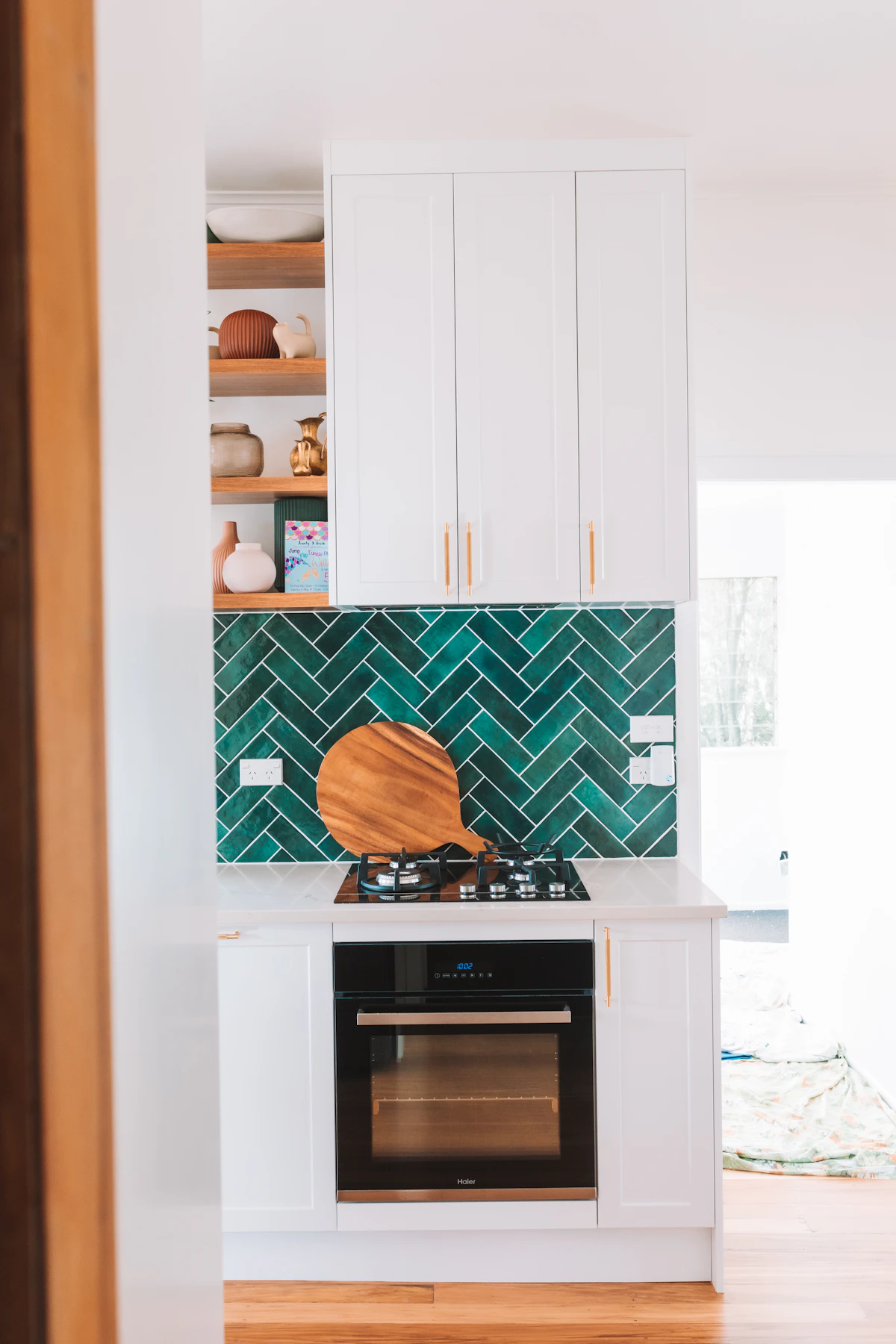 A kitchen with white cabinets and a green tile splashback.