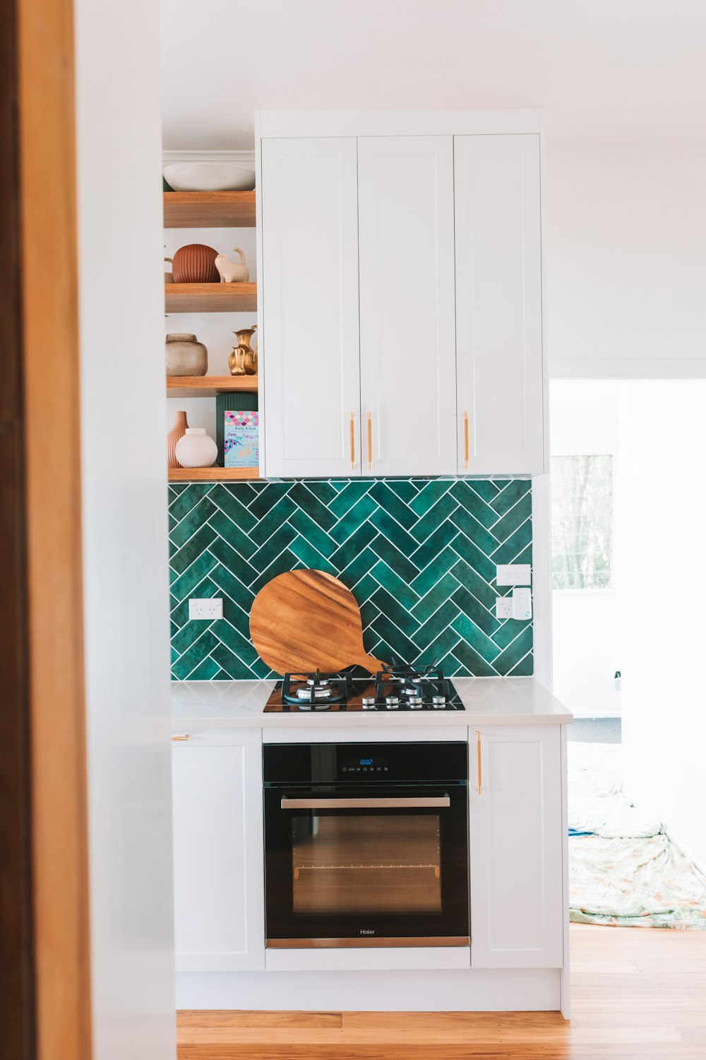 a kitchen with white cabinets and a green tile backsplash