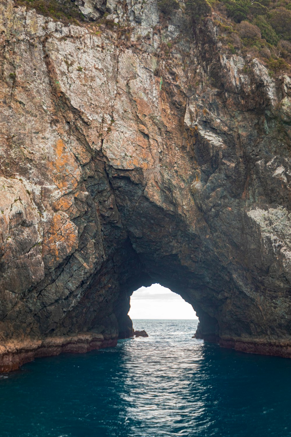 a boat is in the water near a large rock arch