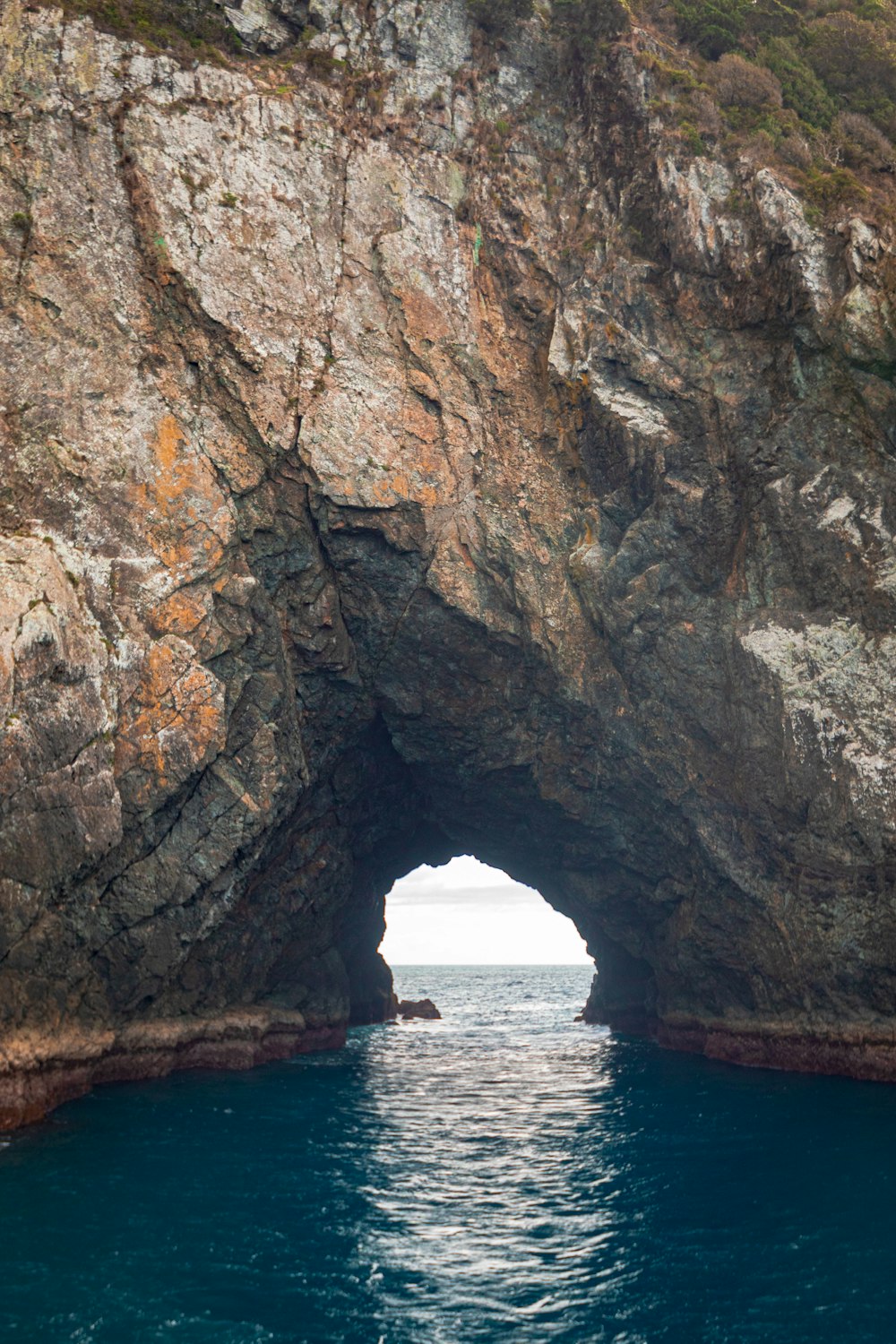 a boat is in the water near a large rock arch