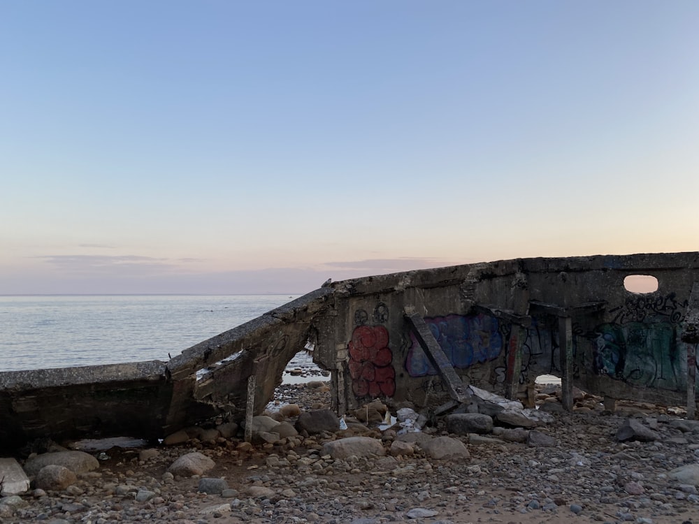 a boat sitting on top of a rocky beach next to the ocean