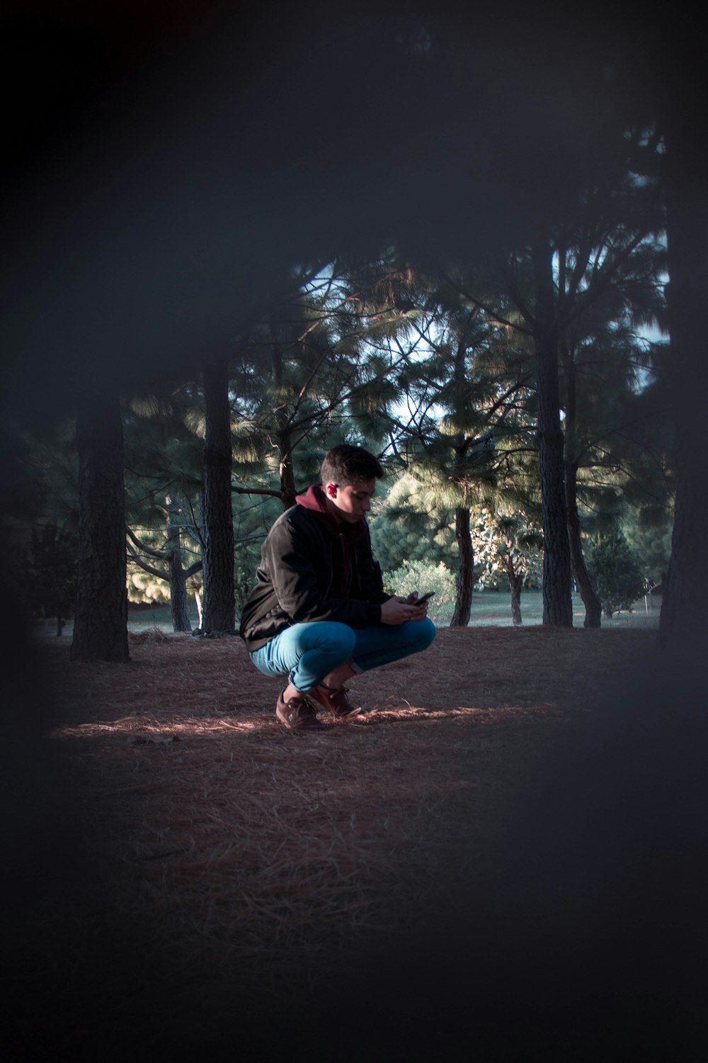 a man squatting down in the middle of a forest