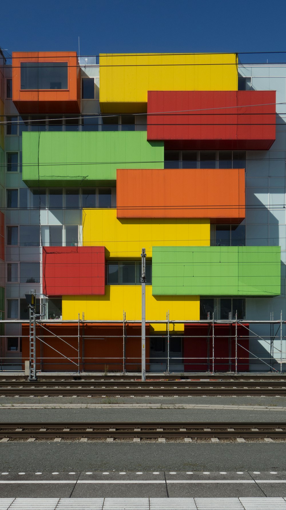 a multicolored building on the side of a train track
