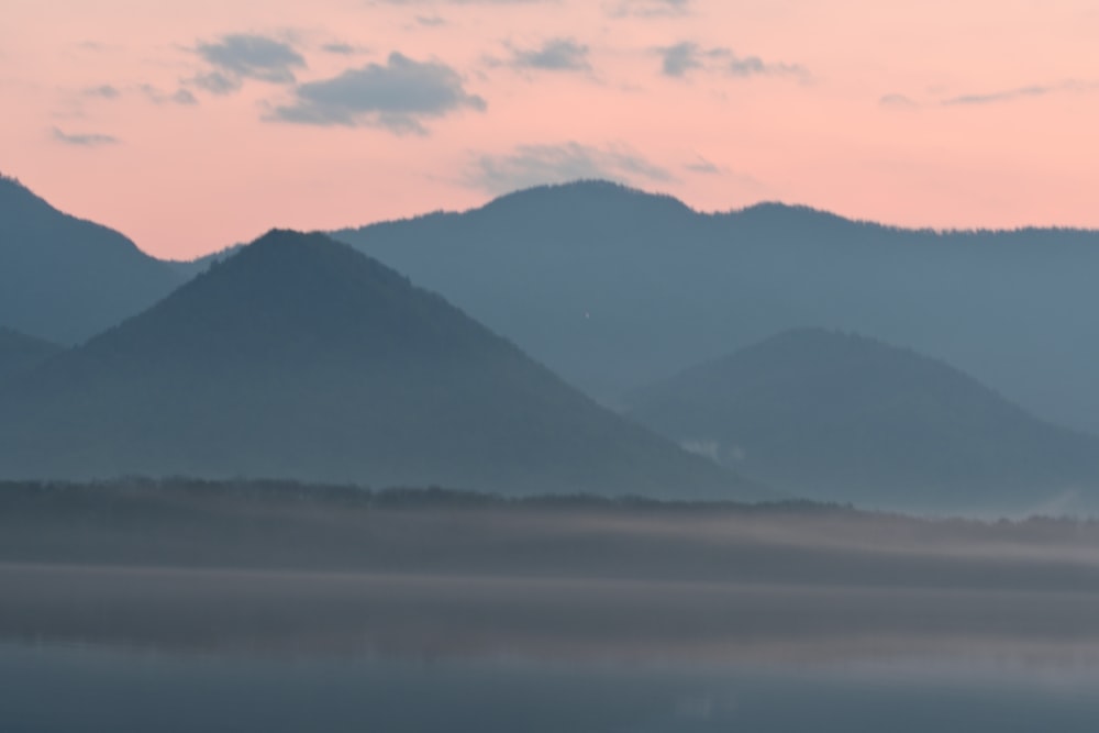 a foggy lake with mountains in the background