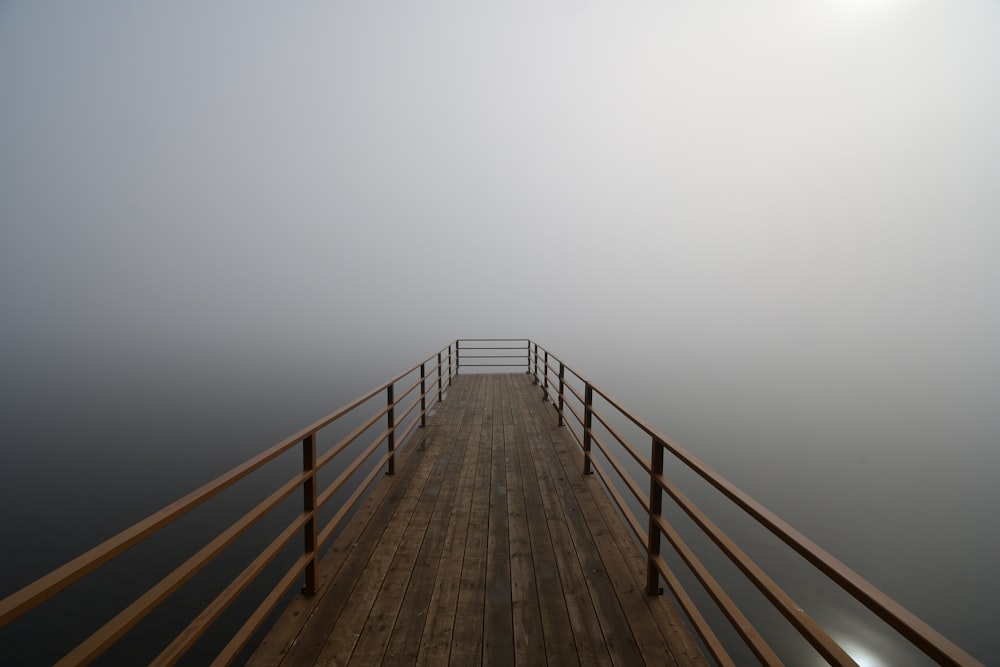 a wooden pier with railings on a foggy day