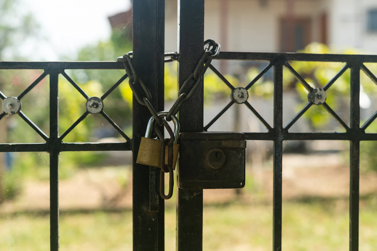 Gembok terpasang pada gerbang dengan rumah di latar belakang