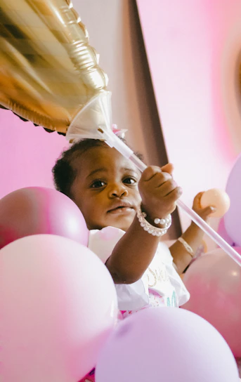 A smiling child holding a colorful kidney-shaped balloon at a community health event.