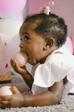 A joyful toddler playing with colorful balloons in a softly lit studio.