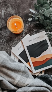 a couple of pamphlets sitting on top of a table next to a candle
