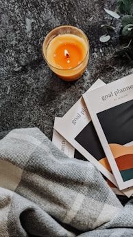 a glass of orange juice next to a stack of books