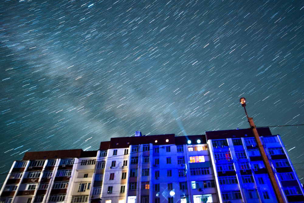 the night sky is filled with stars above a row of apartment buildings
