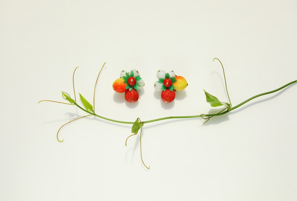 a pair of fruit earrings sitting on top of a green stem
