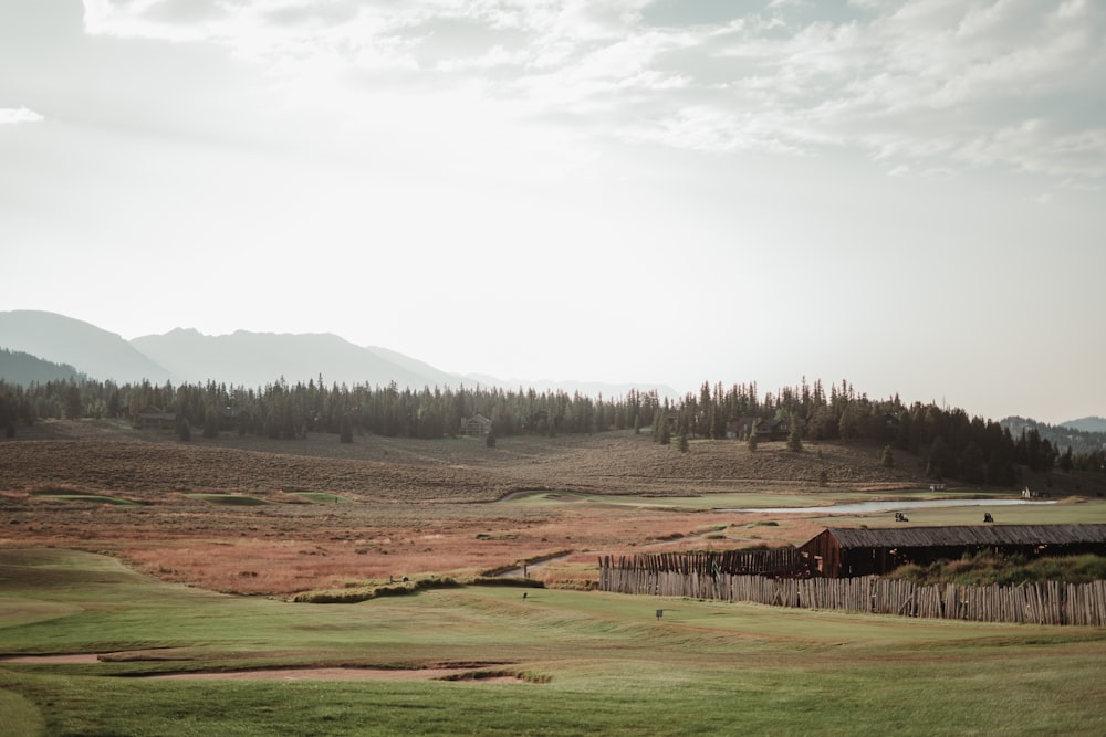 a scenic view of a golf course with a lake and mountains in the background