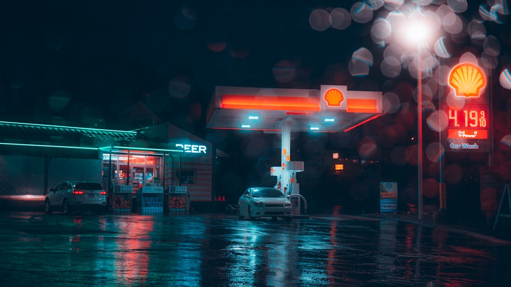 una stazione di servizio di notte con un'auto parcheggiata di fronte ad essa