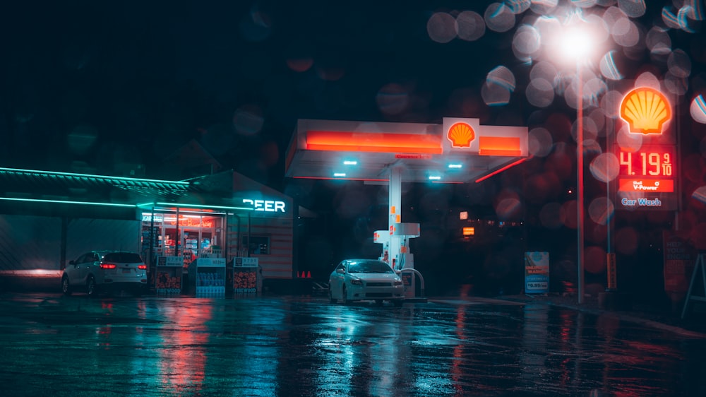 um posto de gasolina à noite com um carro estacionado em frente a ele