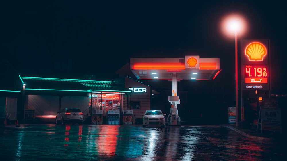 a gas station at night with a car parked in front of it