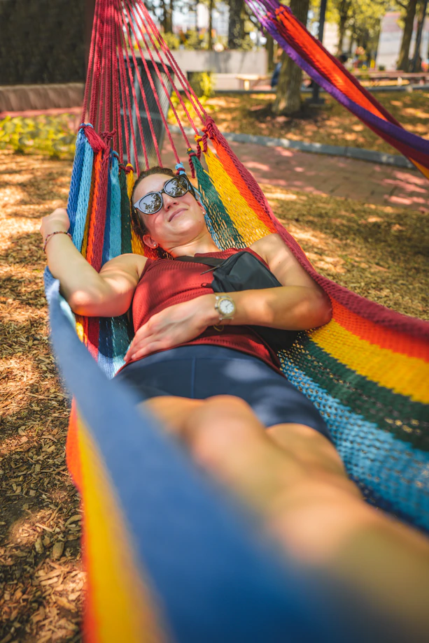 a woman laying in a rainbow colored hammock
