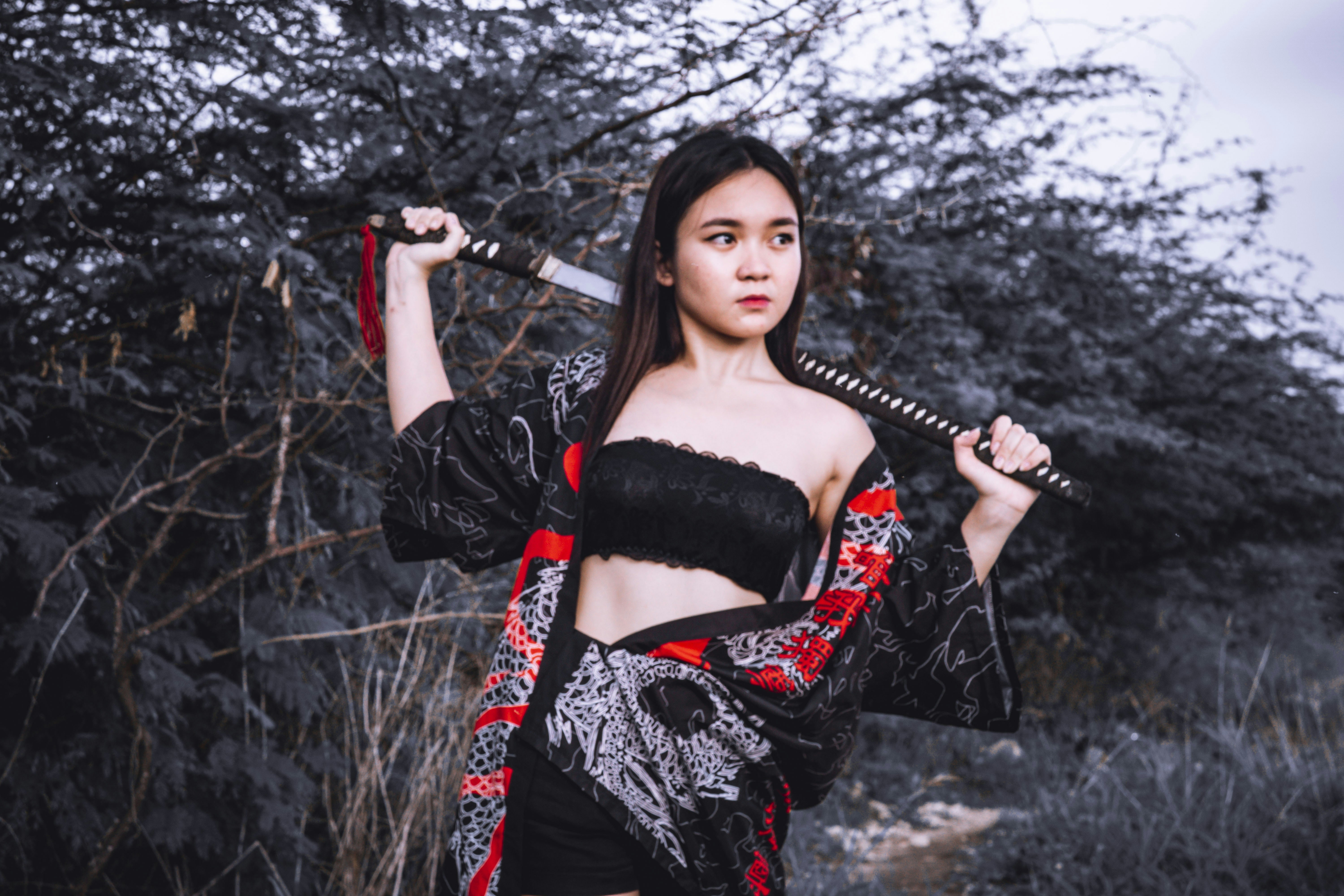 Seorang wanita dengan pakaian hitam dan merah memegang pedang