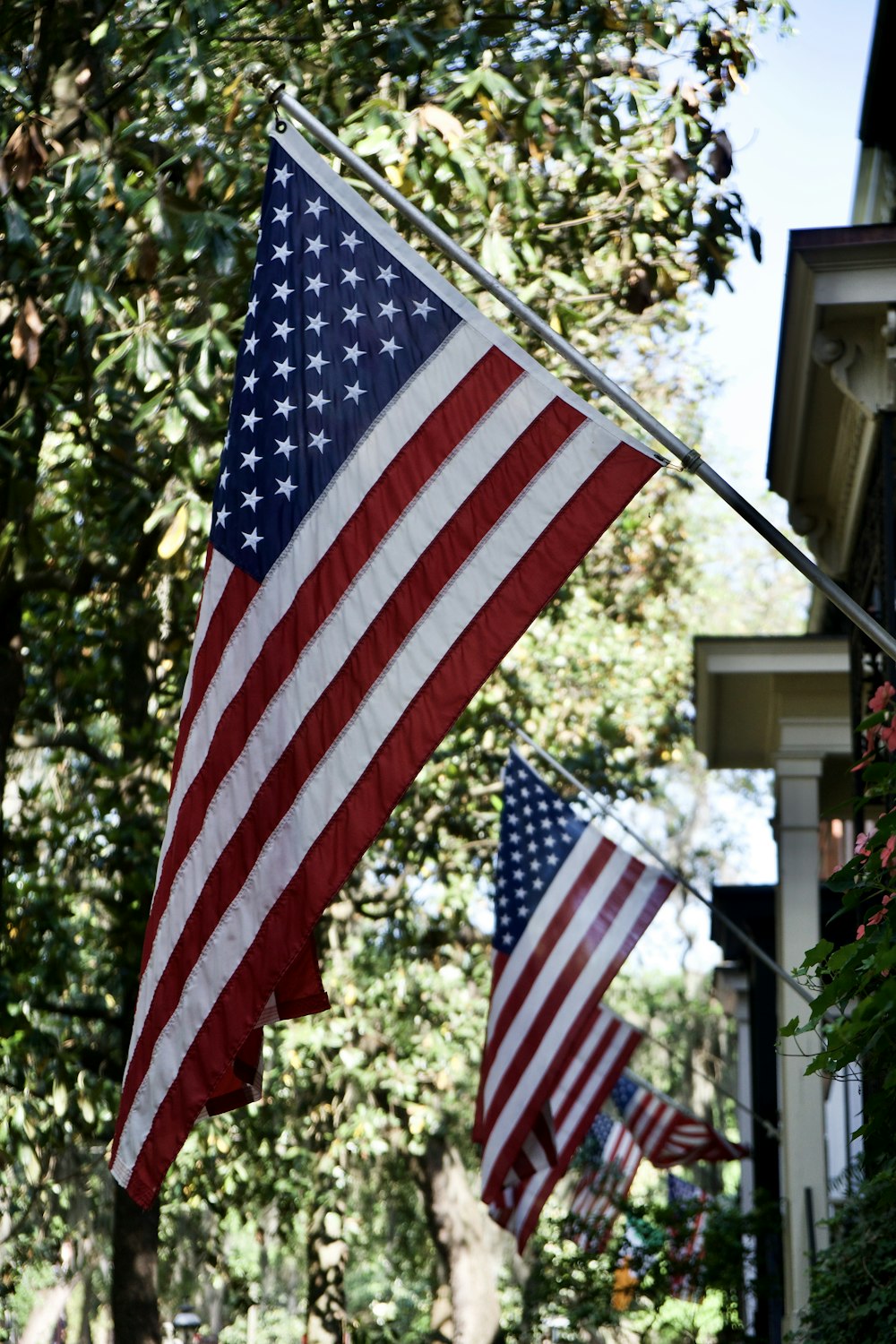 two american flags hanging from a pole in front of a house