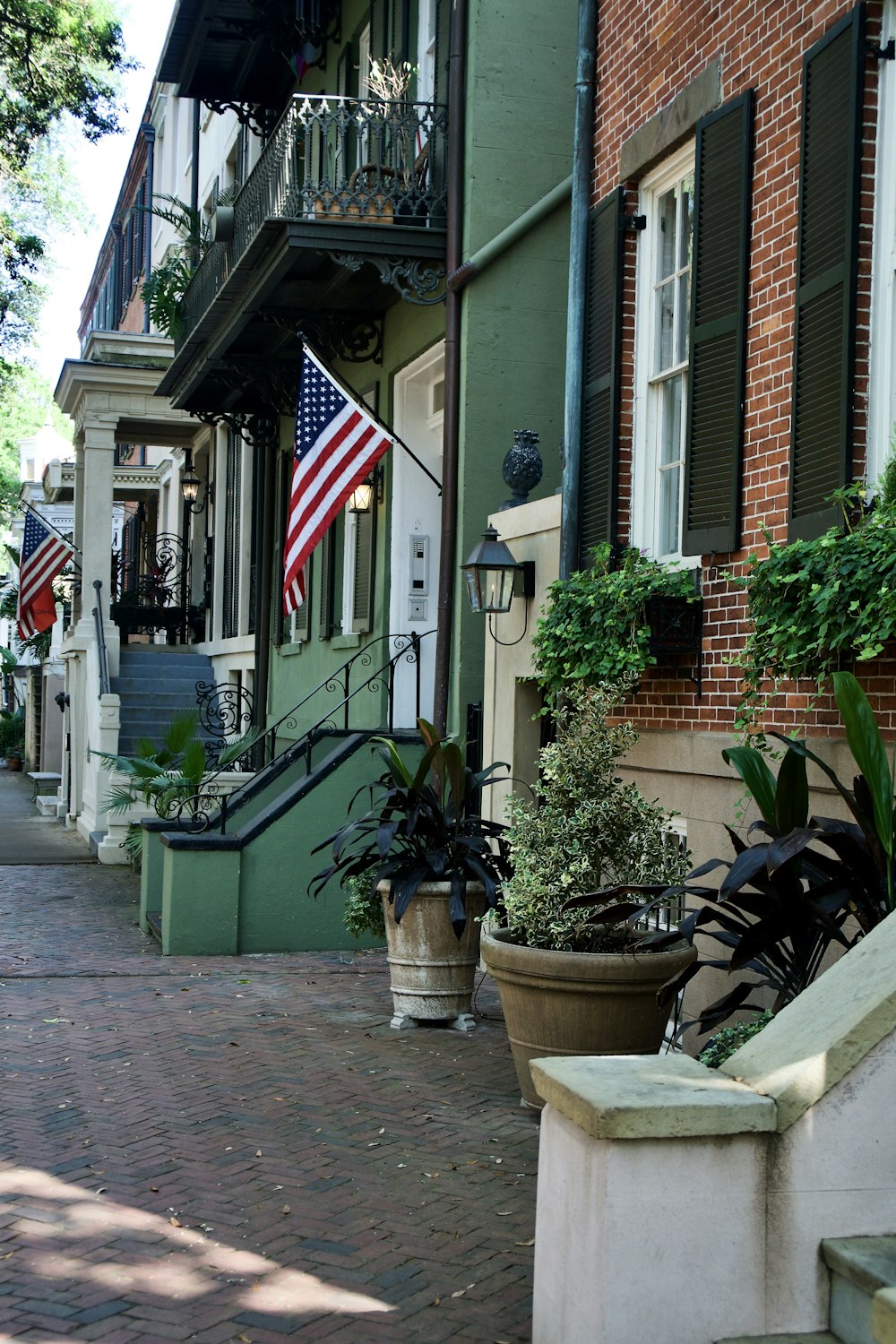 a brick sidewalk with potted plants and an american flag