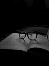 a black and white photo of a book with glasses on it