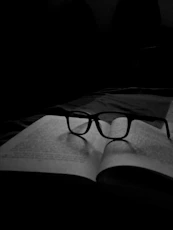 a black and white photo of a book with glasses on it