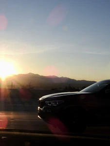 A sleek modern German car driving on a scenic European highway at sunset