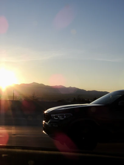 A sleek modern German car driving on a scenic European highway at sunset