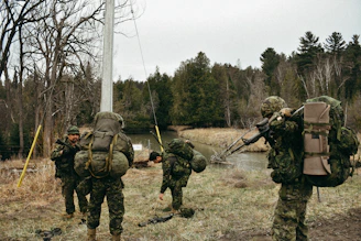 a group of soldiers walking across a grass covered field