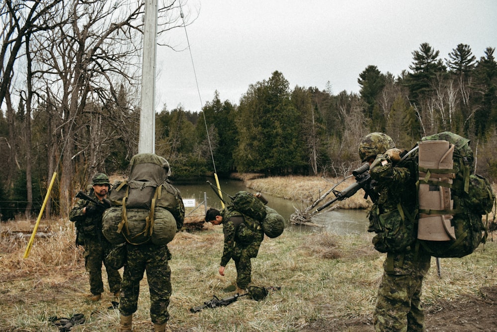 a group of soldiers walking across a grass covered field