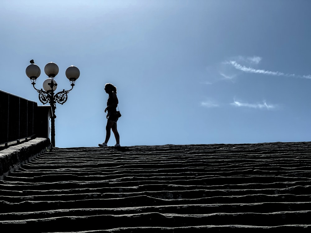 a person walking down a street next to street lamps