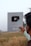 A person holds a YouTube Silver Play Button award, which is given for achieving 100,000 subscribers. The background features a field under a clear sky.