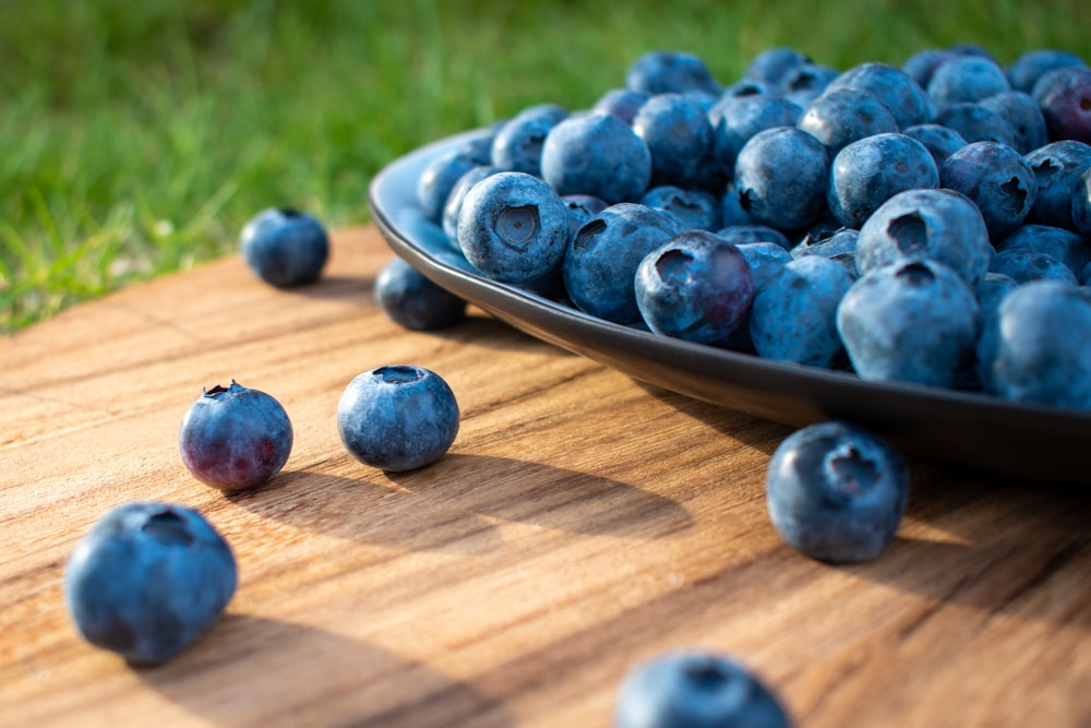 a plate of blueberries on a wooden table