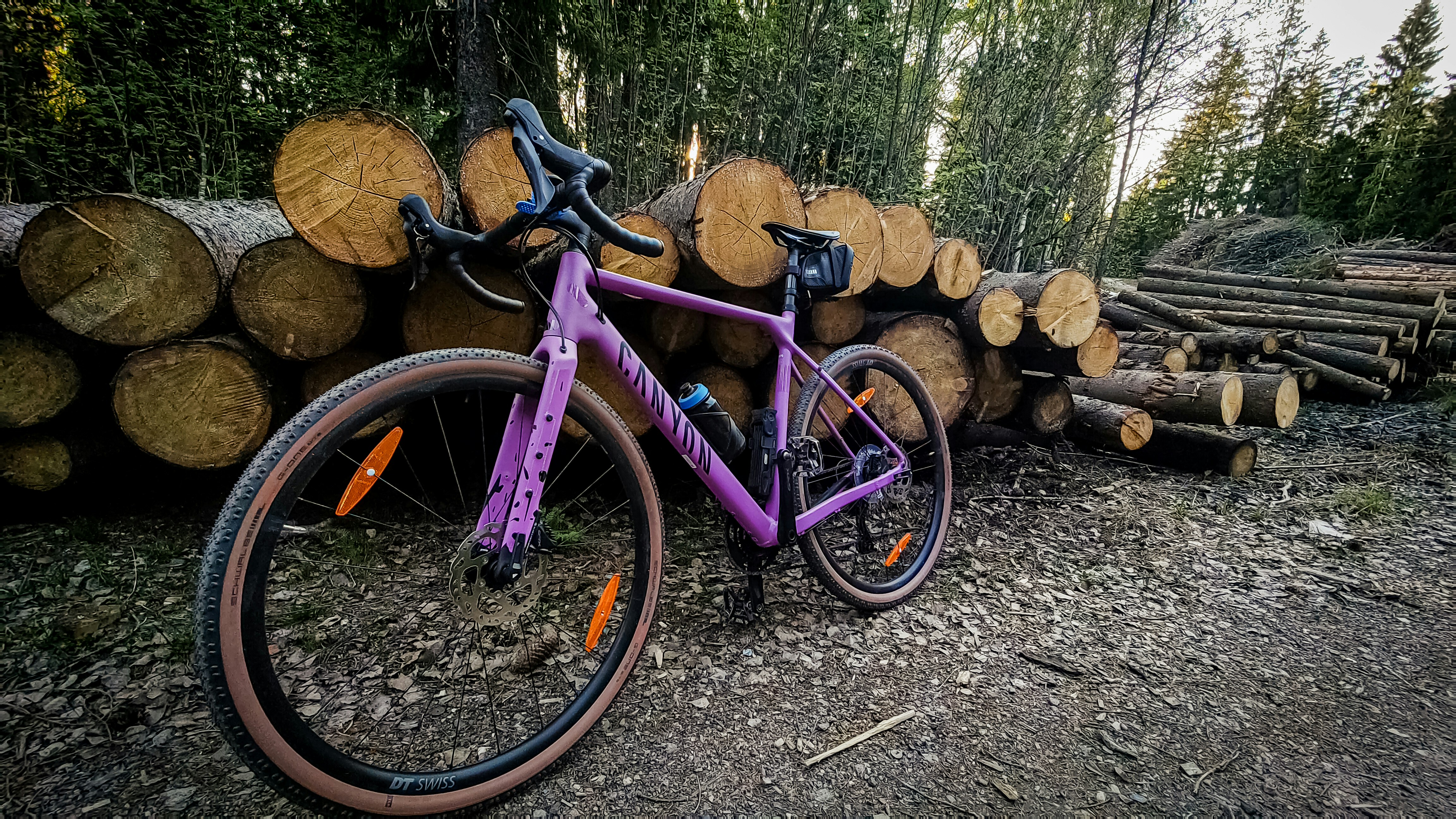 a purple bike parked next to a pile of logs